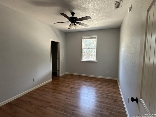 empty room featuring a textured ceiling, dark hardwood / wood-style floors, and ceiling fan