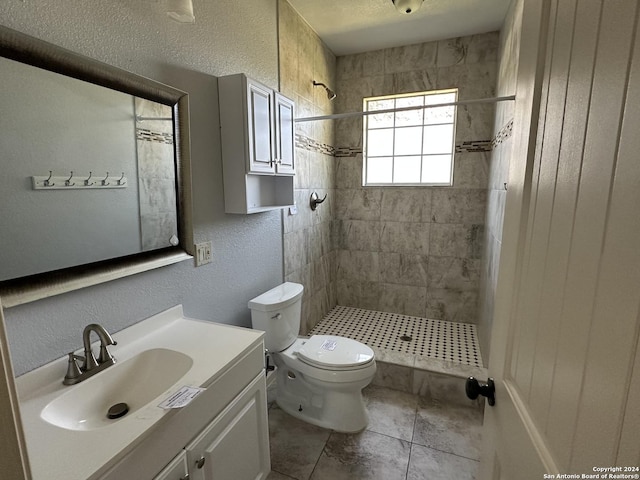 bathroom featuring tile patterned floors, vanity, toilet, and tiled shower