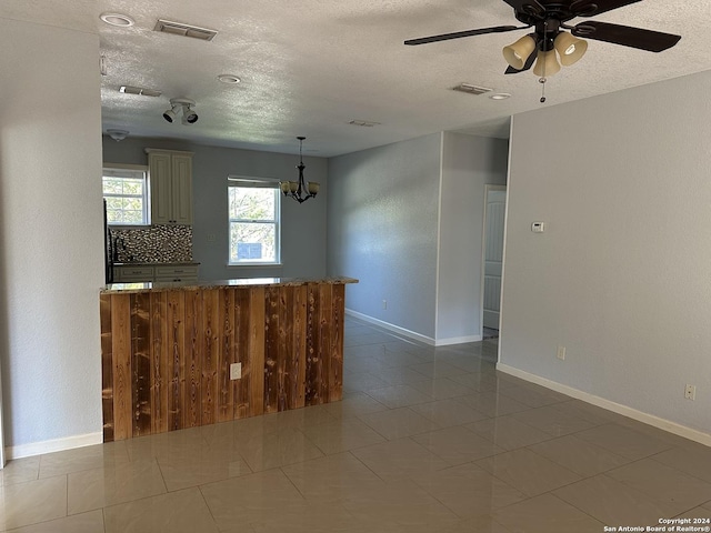 kitchen with backsplash, ceiling fan with notable chandelier, hanging light fixtures, a textured ceiling, and light tile patterned flooring