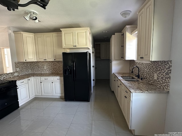 kitchen with stove, tasteful backsplash, black refrigerator with ice dispenser, sink, and light tile patterned floors