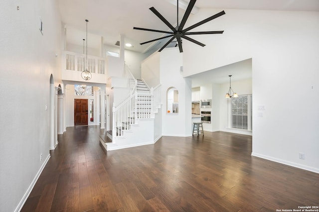 unfurnished living room with beam ceiling, dark hardwood / wood-style flooring, high vaulted ceiling, and ceiling fan with notable chandelier