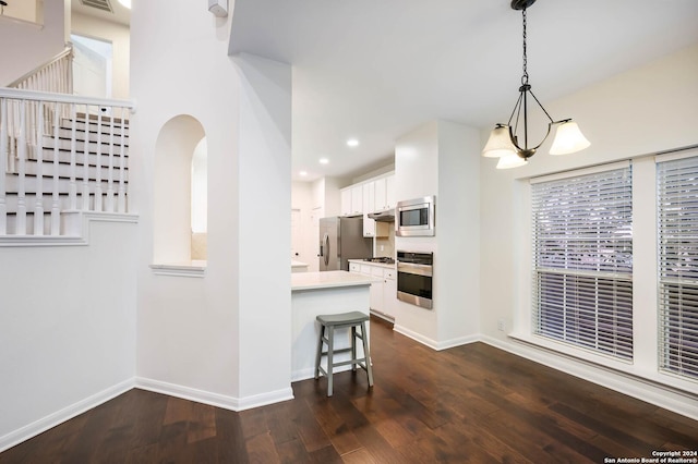 kitchen featuring a breakfast bar, white cabinets, appliances with stainless steel finishes, decorative light fixtures, and a chandelier