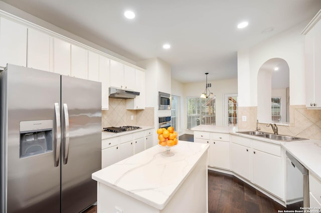 kitchen with sink, hanging light fixtures, white cabinets, a kitchen island, and appliances with stainless steel finishes