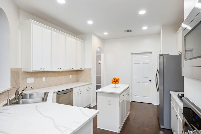 kitchen with light stone countertops, a center island, sink, white cabinets, and appliances with stainless steel finishes