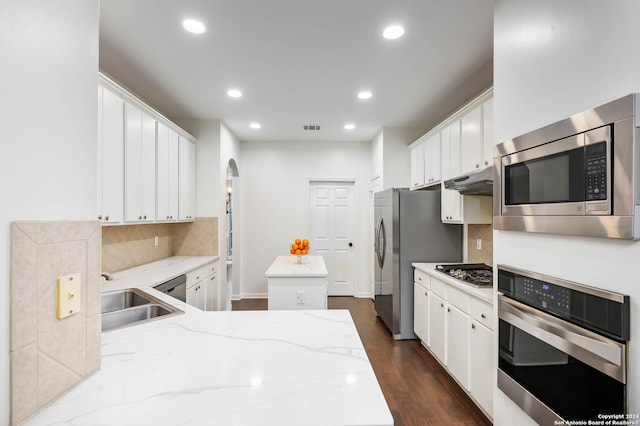 kitchen with sink, dark hardwood / wood-style floors, light stone countertops, appliances with stainless steel finishes, and white cabinetry