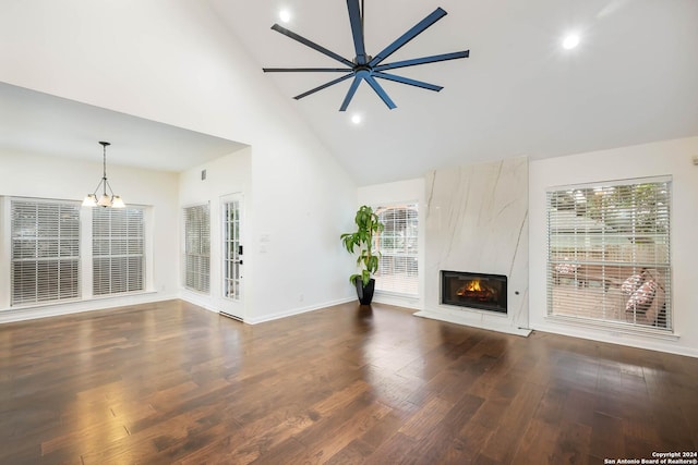 unfurnished living room with high vaulted ceiling, ceiling fan with notable chandelier, dark wood-type flooring, and a high end fireplace