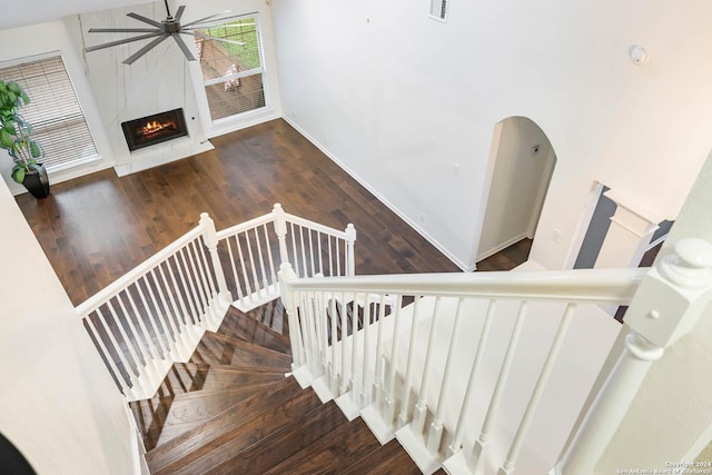 stairway featuring hardwood / wood-style floors, ceiling fan, and a high end fireplace