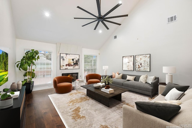 living room with ceiling fan, a fireplace, high vaulted ceiling, and dark wood-type flooring