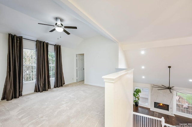 carpeted spare room featuring ceiling fan, a fireplace, and lofted ceiling