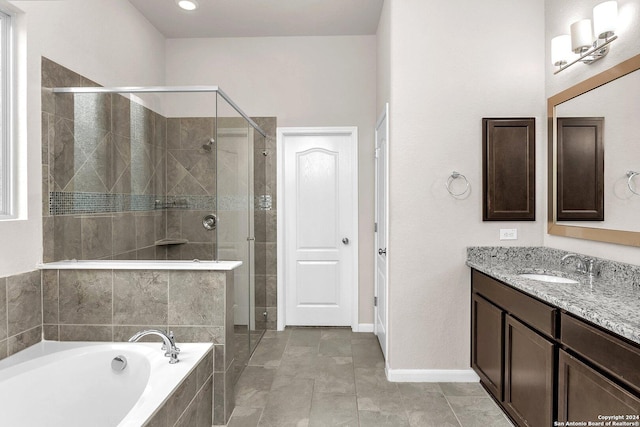 bathroom featuring plus walk in shower, vanity, and tile patterned flooring