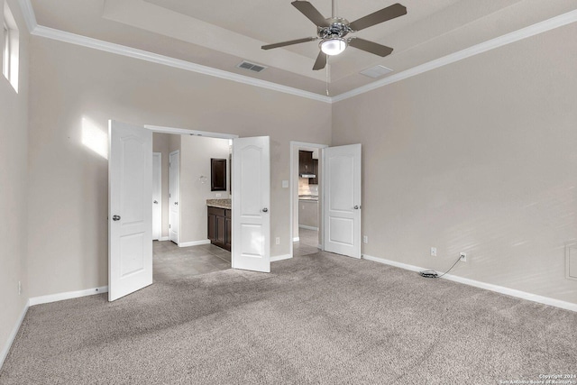 unfurnished bedroom featuring a tray ceiling, ceiling fan, carpet, and ornamental molding