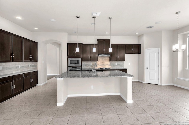 kitchen featuring appliances with stainless steel finishes, light tile patterned floors, hanging light fixtures, and an island with sink