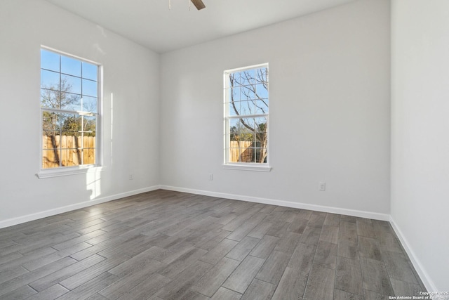 spare room featuring ceiling fan, dark hardwood / wood-style flooring, and a healthy amount of sunlight