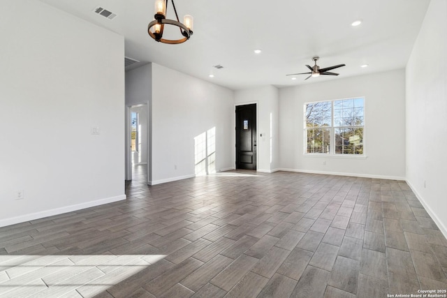 unfurnished living room featuring ceiling fan with notable chandelier