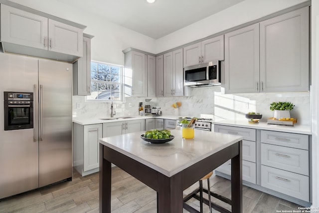 kitchen featuring backsplash, gray cabinets, sink, and appliances with stainless steel finishes