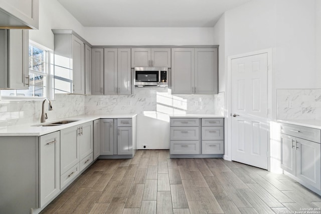 kitchen with backsplash, gray cabinetry, and sink