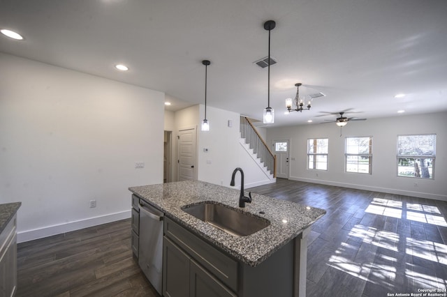 kitchen featuring a kitchen island with sink, ceiling fan with notable chandelier, sink, stainless steel dishwasher, and decorative light fixtures