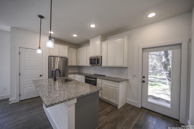 kitchen with backsplash, stainless steel appliances, sink, pendant lighting, and white cabinets