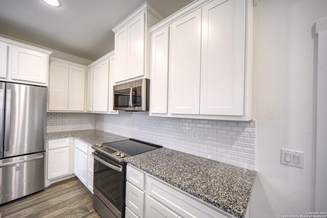 kitchen with appliances with stainless steel finishes, tasteful backsplash, light stone counters, dark wood-type flooring, and white cabinets