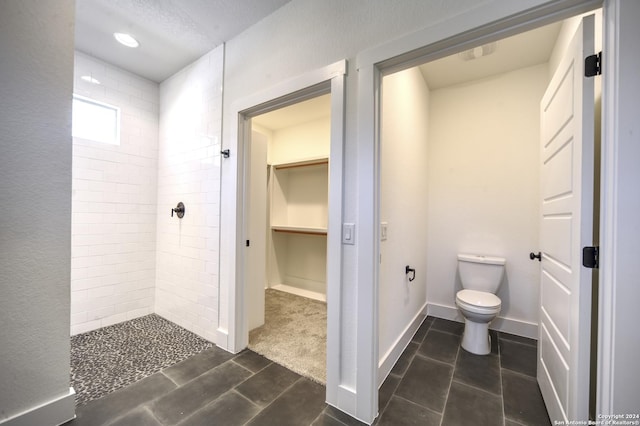 bathroom featuring tiled shower and toilet