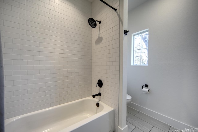 bathroom featuring tile patterned floors, tiled shower / bath combo, and toilet