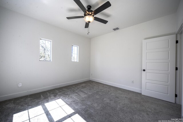 unfurnished room featuring ceiling fan and dark carpet