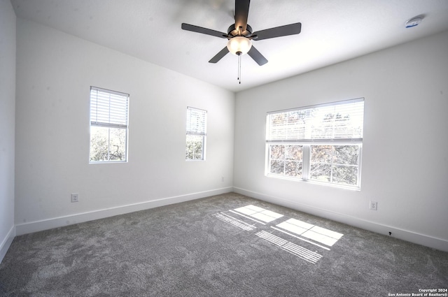 unfurnished room with dark colored carpet and ceiling fan