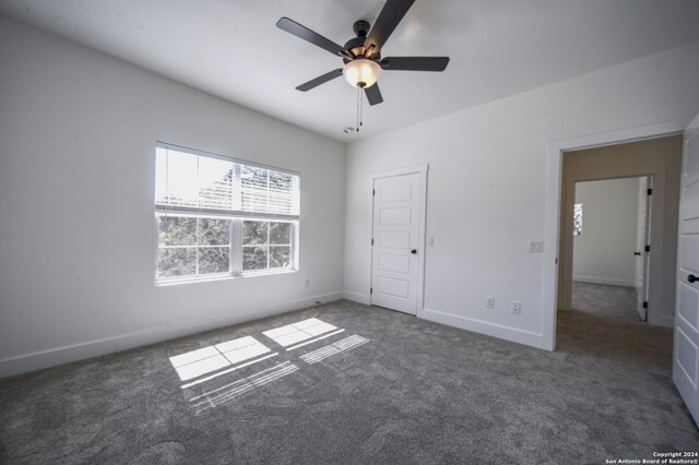 unfurnished bedroom with ceiling fan and dark carpet