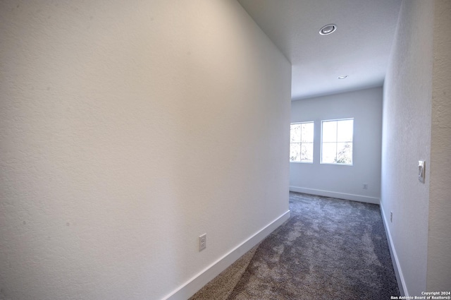 hall featuring dark colored carpet