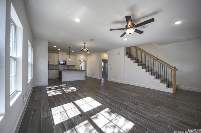 unfurnished living room featuring ceiling fan with notable chandelier