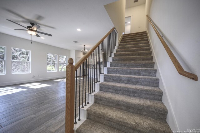 stairway featuring hardwood / wood-style floors and ceiling fan with notable chandelier