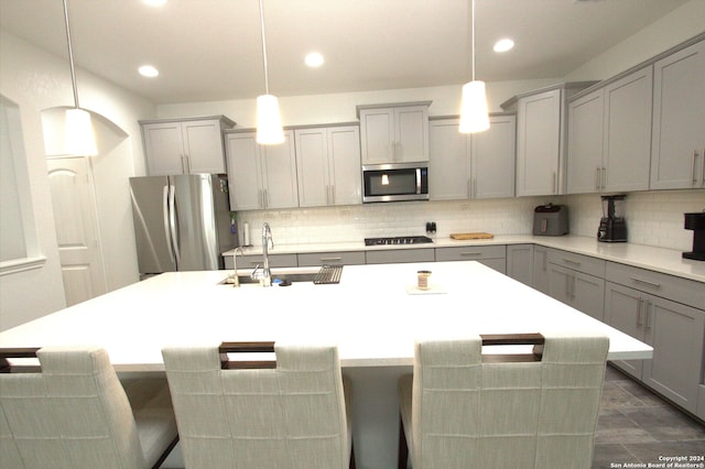 kitchen with gray cabinetry, sink, decorative light fixtures, a center island with sink, and appliances with stainless steel finishes