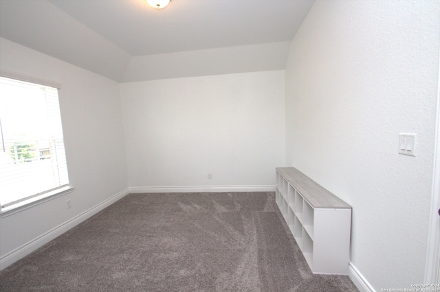 carpeted empty room featuring vaulted ceiling