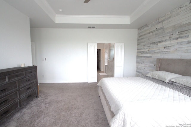 carpeted bedroom featuring a tray ceiling, ceiling fan, ornamental molding, and wood walls