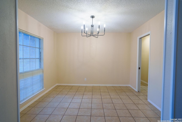 unfurnished room with a chandelier, light tile patterned floors, and a textured ceiling