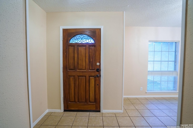 foyer with light tile patterned floors, a textured ceiling, and a healthy amount of sunlight