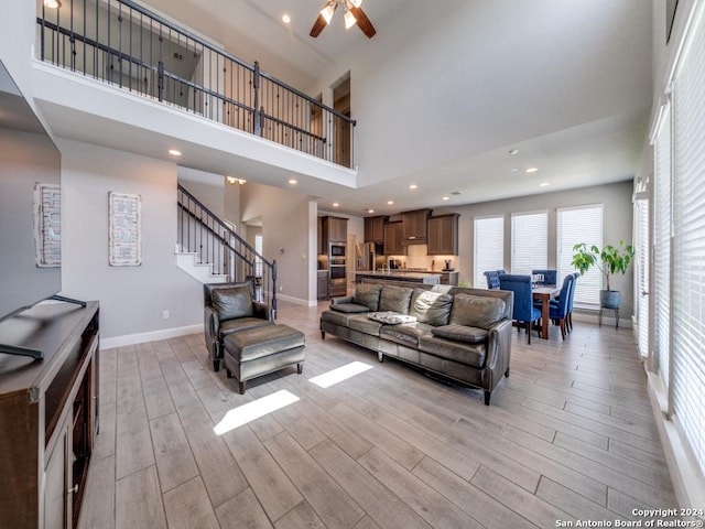 living room featuring ceiling fan and a towering ceiling