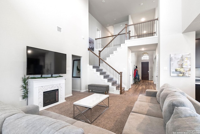 living room featuring wood-type flooring, a high ceiling, and a tiled fireplace