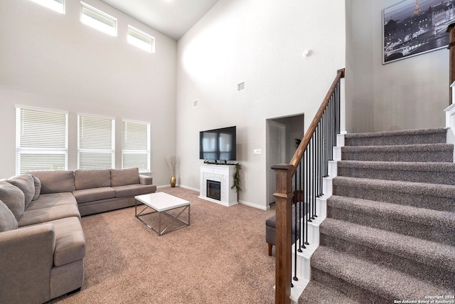 living room with carpet floors, plenty of natural light, and a towering ceiling