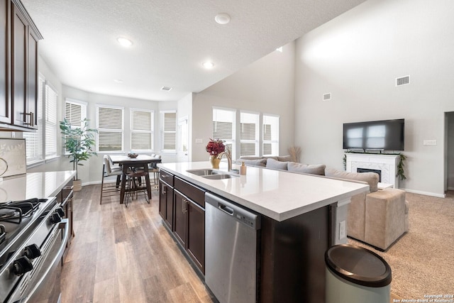 kitchen with a center island with sink, dark brown cabinets, stainless steel appliances, and a textured ceiling