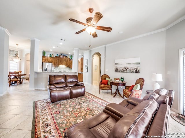 tiled living room with ceiling fan with notable chandelier and ornamental molding