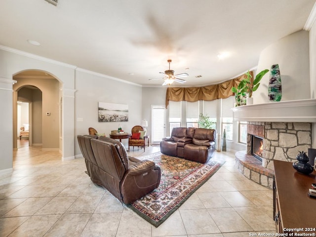 tiled living room featuring a fireplace, decorative columns, ceiling fan, and crown molding