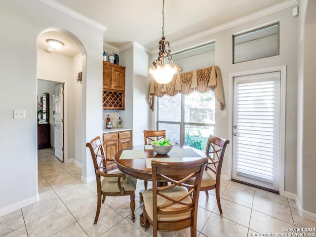 tiled dining space with bar, ornamental molding, and a notable chandelier