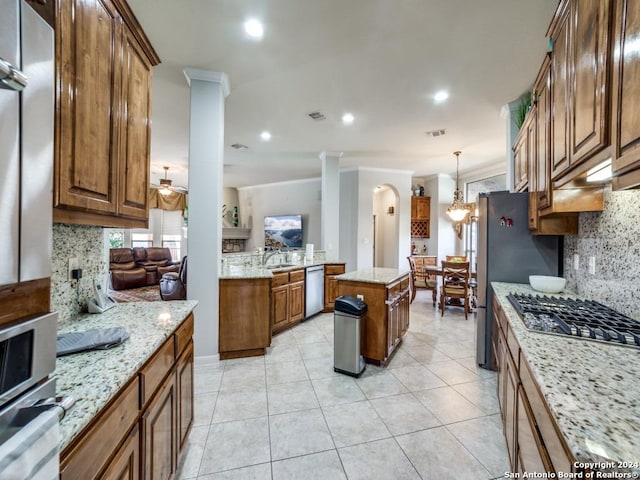 kitchen featuring ceiling fan with notable chandelier, a kitchen island, light stone countertops, and appliances with stainless steel finishes