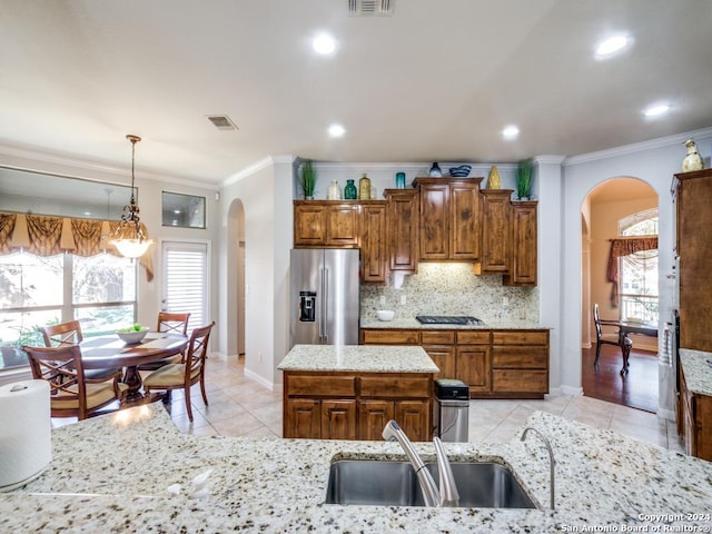 kitchen with stainless steel fridge, sink, light tile patterned floors, pendant lighting, and a kitchen island