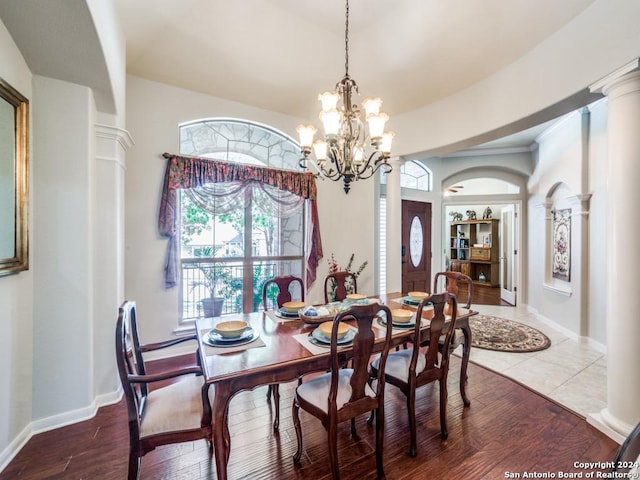 dining area featuring decorative columns, wood-type flooring, and a notable chandelier