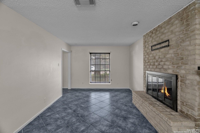 unfurnished living room with a fireplace, dark tile patterned floors, and a textured ceiling