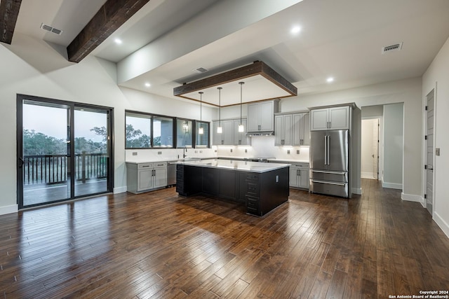 kitchen featuring a center island, dark wood-type flooring, gray cabinets, appliances with stainless steel finishes, and beamed ceiling