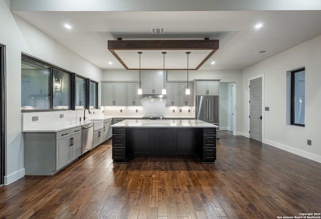 kitchen with pendant lighting, a kitchen island, dark hardwood / wood-style flooring, and appliances with stainless steel finishes