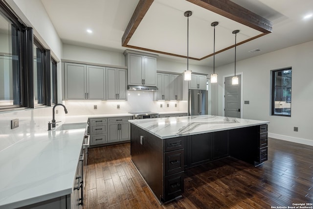 kitchen featuring light stone countertops, high end refrigerator, dark hardwood / wood-style flooring, decorative light fixtures, and a large island